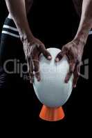 Mid section of sportsman keeping rugby ball on kicking tee
