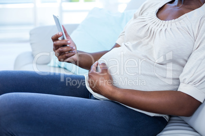 Mid section of pregnant woman touching belly