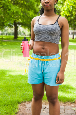 Fit woman measuring her waist