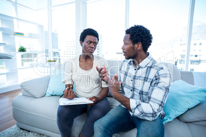 Man talking with pregnant wife while writing on paper