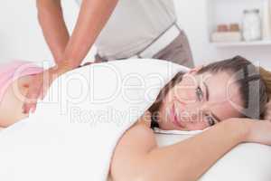 Physiotherapist doing back massage to his smiling patient