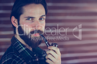 Portrait of confident hipster with smoking pipe