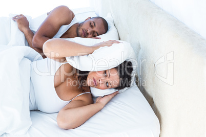 Stressed wife sleeping besides snoring husband