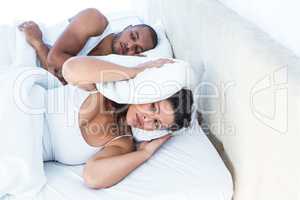 Stressed wife sleeping besides snoring husband