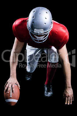 American football player taking position while holding ball