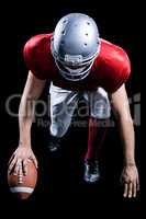 American football player taking position while holding ball
