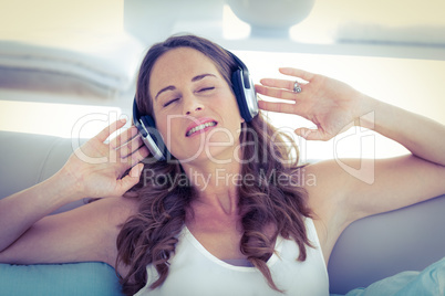 Woman with eyes closed listening to music on sofa