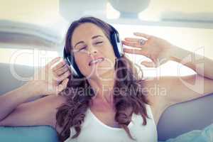Woman with eyes closed listening to music on sofa