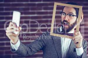 Smart man taking selfie while holding frame