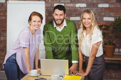 Portrait of happy business people leaning on desk