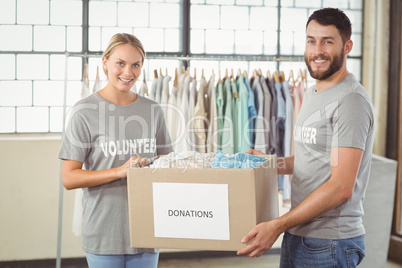 Portrait of smiling volunteer holding clothes donation box