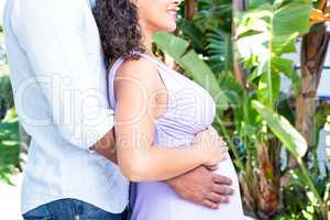 Midsection of husband with pregnant wife touching belly