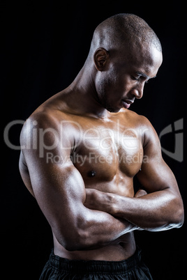 Shirtless athlete standing with arms crossed while eyes closed