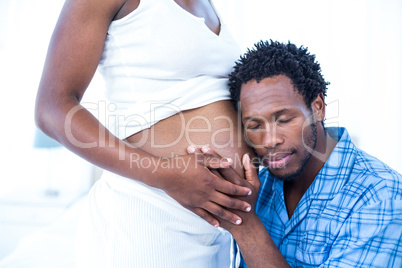 Husband with closed eyes listening to his pregnant wife