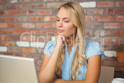 Woman with hand on chin looking at laptop