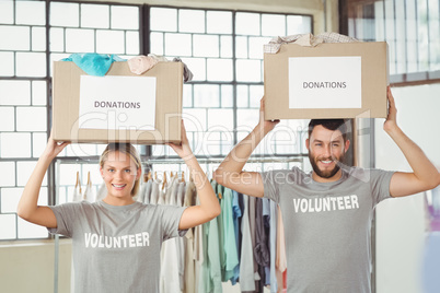 Portrait of volunteers carrying donation boxes on head