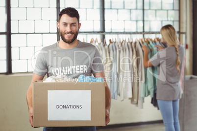 Portrait of man holding clothes donation box in office