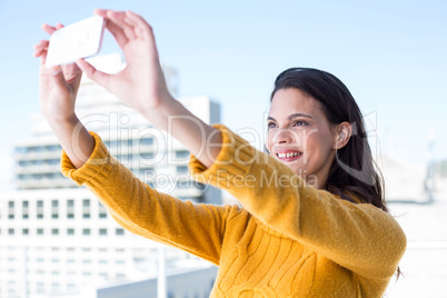 Pretty brunette taking photos with her smartphone