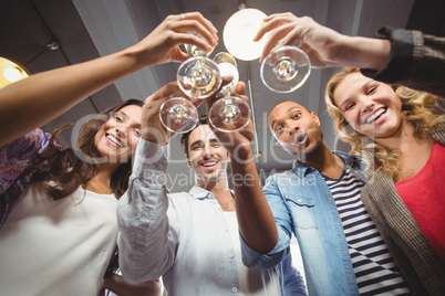 Low angle portrait of happy colleagues toasting with champagne i