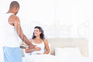 Husband serving breakfast for happy pregnant wife