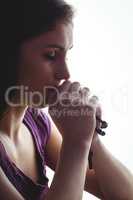 Woman praying with wooden rosary beads