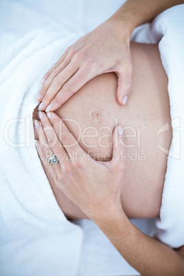 Pregnant woman making heart shape on belly