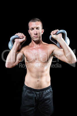 Confident shirtless sportsman holding kettlebell