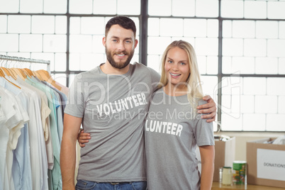 Portrait of joyful volunteers with arms around standing