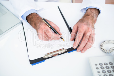High angle view of doctor writing on paper at clinic High angle view of doctor writing on paper at clinic
