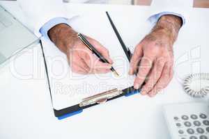 High angle view of doctor writing on paper at clinic