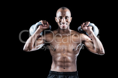 Portrait of happy muscular man exercising with kettlebells