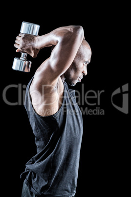 Side view of muscular man exercising with dumbbell