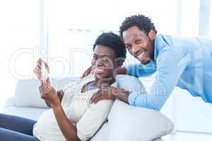 Pregnant woman with husband holding photo at home