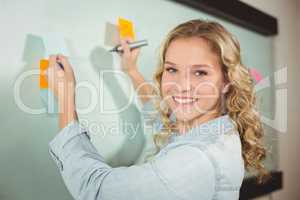 Portrait of beautiful woman holding sticky note while writing on