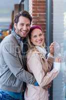 Smiling couple embracing and going window shopping