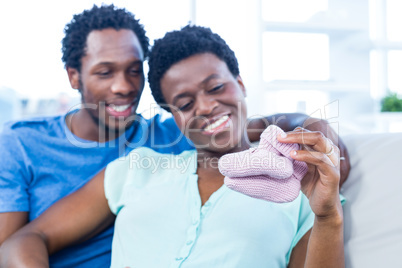 Couple looking at baby shoes while resting on sofa