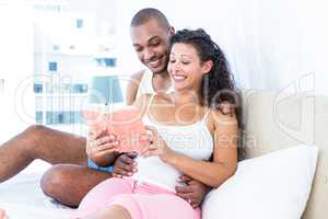 Happy husband with pregnant wife reading book