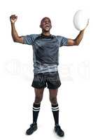 Cheerful sportsman with clenched fist holding rugby ball