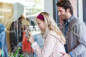 Smiling couple going window shopping and pointing at clothes