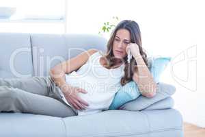 Sad pregnant woman lying on sofa