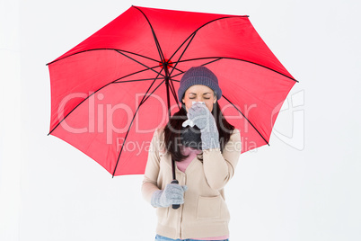 Sick brunette blowing her nose while holding an umbrella