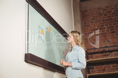 Low angle view of businesswoman standing by glass board in offic