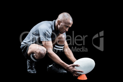 Rugby player keeping ball on kicking tee