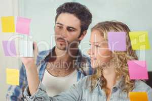 Man looking at woman writing on sticky notes
