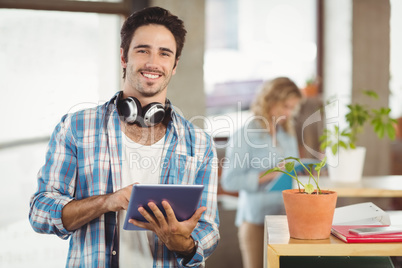 Portrait of happy businessman holding digital tablet creative of