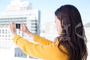 Pretty brunette taking photos with her smartphone