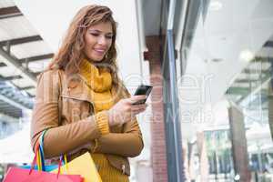 Smiling woman with shopping bags using smartphone
