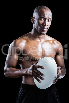 Portrait of confident shirtless athlete holding rugby ball