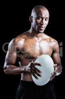 Portrait of confident shirtless athlete holding rugby ball