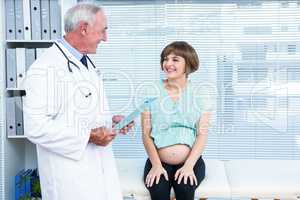 Happy doctor holding folder by pregnant woman